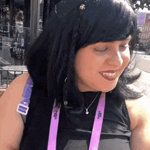 a woman wearing a black tank top and a purple lanyard that says ' sydney ' on it