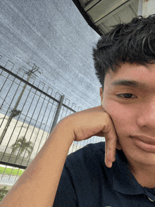 a young man rests his head on his hand and looks at the camera