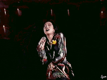 a woman singing into a microphone in front of a wall of lights