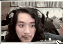 a man with long hair and a mustache is wearing headphones .