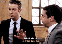 a man in a suit says he 'll show if you say so while another man looks on