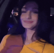a woman in a yellow shirt is sitting in the back seat of a car .