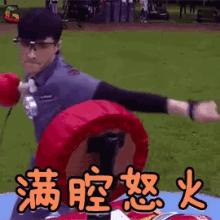 a man wearing glasses is holding a boxing glove in front of a sign with chinese writing on it