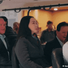 a group of people are sitting on a bus with the number 1-3 on the ceiling