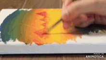 a person is painting a rainbow of colors on a canvas with the words made in animotica in the corner