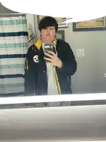 a man taking a selfie in front of a mirror wearing a jacket with a steelers logo on it
