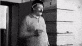 a man with a mustache is smoking a cigarette while wearing a hat .