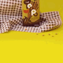 a box of pop sticks sits next to a cup on a table