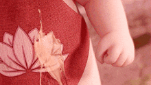 a baby 's hand is holding a piece of food that has spilled out of his shirt .