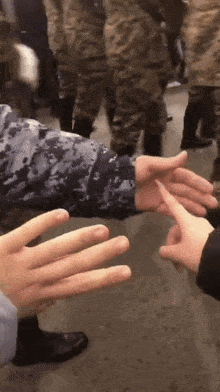 a man in a camo jacket is reaching out to shake another man 's hand