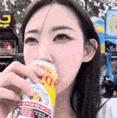 a woman is drinking from a can that says ' d ' on the side