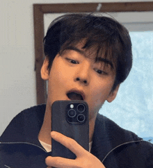 a young man is taking a selfie in front of a mirror with his phone .