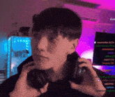 a man wearing headphones with the name bumblebee_b27a on the wall behind him