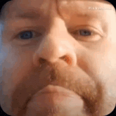 a close up of a man 's face with blue eyes and a beard .
