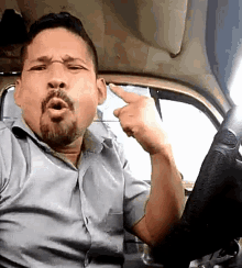 a man with a beard is sitting in a car and pointing