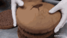 a person is holding a piece of chocolate cake with a dinosaur carved into it .