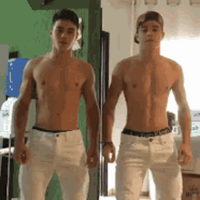 two shirtless men are standing next to each other in a room .
