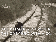 a man is kneeling on train tracks with a gun in his hand .