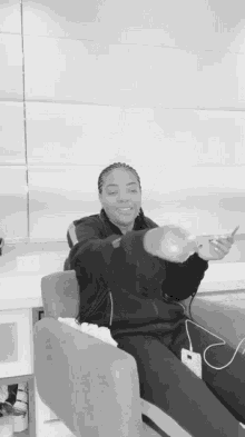 a black and white photo of a woman sitting in a chair holding a cell phone