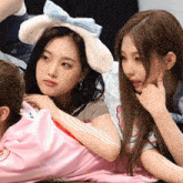 a girl wearing a bunny ear headband sits next to a girl wearing a shirt with the letter m on it