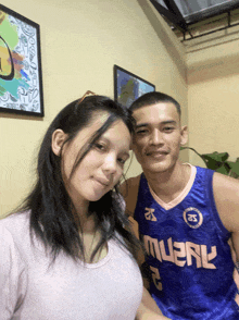 a man and a woman pose for a picture with the man wearing a blue jersey that says muenl
