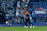 a group of soccer players are celebrating on a field with a joma winama sign in the background