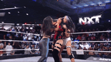 two women are wrestling in a ring with nxt written in the background