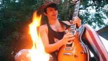 a man in a cowboy hat is playing a guitar