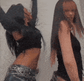 two women are standing next to each other with their arms in the air
