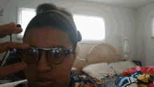 a woman wearing a headband and sunglasses looks at the camera in front of a bed