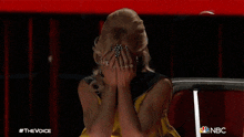 a woman in a yellow and black dress is sitting in a chair on the voice
