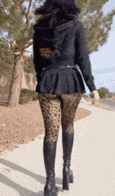 a woman wearing leopard print tights and black boots is walking down the sidewalk