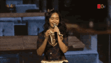 a girl singing into a microphone with the word live on the bottom right