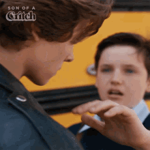 two boys are standing in front of a yellow school bus with son of a critch written on the bottom