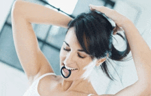 a woman is smiling while holding her hair in a ponytail