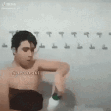 a man without a shirt is standing in front of a wall with hooks hanging on it .
