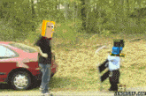 a man with a paper bag on his head stands next to a child with a sword and shield