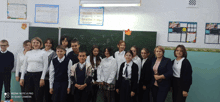 a group of students are posing for a picture in front of a blackboard that says " a " on it