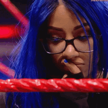 a woman with blue hair and glasses is standing in a ring