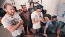 a group of men are standing around a table with one man wearing a shirt that says gear on it