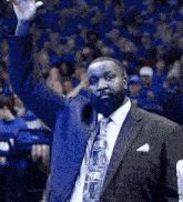 a man in a suit and tie waves his hand in the air