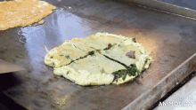 a pan of food is being cooked on a griddle and the words made in animotica are on the bottom