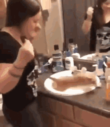 a woman is brushing her teeth in front of a mirror .