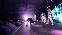 a man kneeling on a stage with a group of dancers