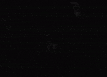 a man in a hoodie is standing in the dark and looking at the camera .