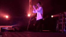 a man singing into a microphone while holding a guitar with the letter d below him