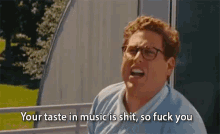 a man with glasses is saying your taste in music is shit , so fuck you