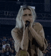 a woman singing into a microphone with a tattoo on her arm that says ' t & a ' on it