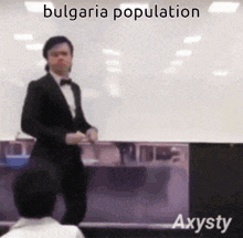 a man in a tuxedo is standing in front of a white board with the words bulgaria population written above him