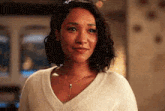 a woman wearing a white sweater and a necklace is smiling and looking at the camera .